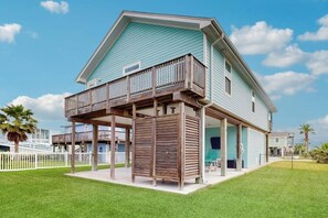 A two-story house with a balcony, a covered porch, and a fenced yard. - Blue Sunrise - Bay Views, Pool & Dog-Friendly (Galveston)