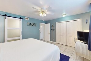 A bedroom with a bed, a ceiling fan, a TV, and a wardrobe. - Seahorse Condominiums 105 (Corpus Christi)
