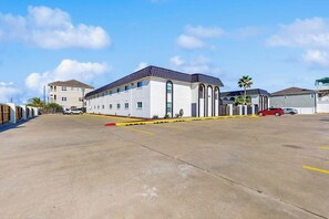 A parking lot with a building that has a flat roof and large windows. - Seahorse Condominiums 105 (Corpus Christi)