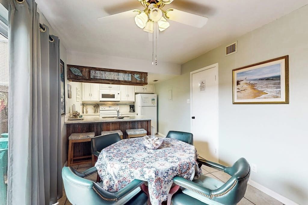 A dining area with a table, chairs, and a ceiling fan.