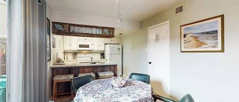 A dining area with a table, chairs, and a ceiling fan.