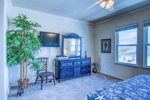 A bedroom with a bed, dresser, chair, and a large window. - Palm Bay 202 - Heated Pool, BBQ & Beach Access (Corpus Christi)