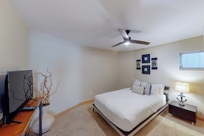 Ein Schlafzimmer mit einem Bett, Deckenventilator, Fernseher, Lampe und Wandbildern.