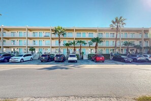 A multi-story hotel with a parking lot in front. - Fiesta Sol Condominiums #109 (South Padre Island)