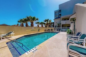 A swimming pool with a 6 ft depth marker, lounge chairs, and palm trees. - Sun Dancer Condominiums 1 (South Padre Island)