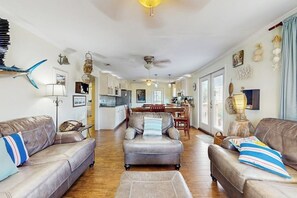 Ein großzügiger Wohnbereich mit Ledersofas, einem Esstisch und einer Küche im Hintergrund.
