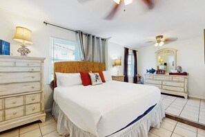 Ein Hotelzimmer mit einem großen Bett, einem Schminktisch, einem Spiegel und einem Deckenventilator.
