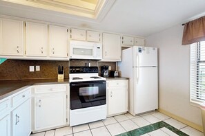 A kitchen with white cabinets, a stove, microwave, and refrigerator. - Saida Towers III #3116 (South Padre Island)