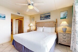 Ein Schlafzimmer mit einem Bett, zwei Nachttischen, einem Deckenventilator und Kunstwerken an den Wänden.