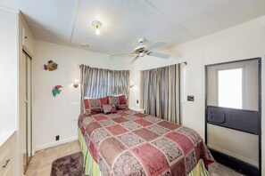 A bedroom with a bed, curtains, a ceiling fan, and wall decorations. - Long Island Village 621 Sand Dollar (Port Isabel)