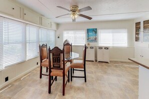 A dining area with a glass table and chairs, a ceiling fan, and white cabinetry. - Long Island Village 621 Sand Dollar (Port Isabel)