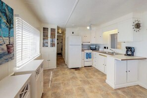 A compact kitchen with white cabinetry, a built-in oven, and a microwave. - Long Island Village 621 Sand Dollar (Port Isabel)