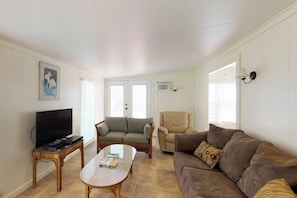 A living room with a television, two sofas, a coffee table, and a door with a window. - Long Island Village 621 Sand Dollar (Port Isabel)