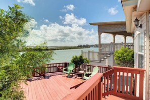 A wooden deck with outdoor furniture overlooking a body of water. - Long Island Village 621 Sand Dollar (Port Isabel)