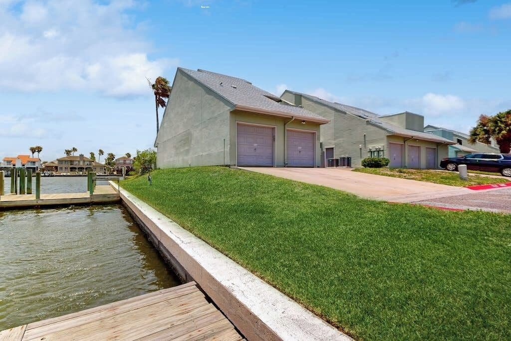A modern building with a flat roof, two garage doors, and a grassy area in front.
