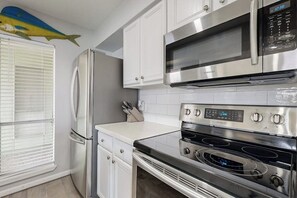 A kitchen with white cabinets, a stainless steel refrigerator, a microwave, and a double oven. - Puente Vista 137- Wilson's Watering Hole - Fishing Spot (Corpus Christi)