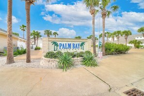 Schild für Palm Bay Village mit Palmen und blauem Himmel.
