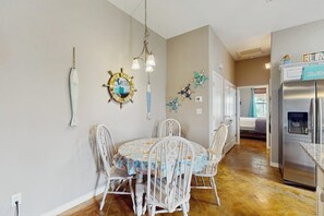 A dining area with a round table, white chairs, and nautical-themed wall decorations. - Casa de la Encla - Anegada (Corpus Christi)