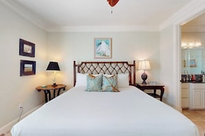 Ein Hotelzimmer mit einem großen Bett, einem Holzkopfschild, zwei Nachttischen mit Lampen und einem Bild an der Wand.