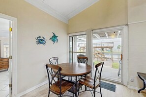 A dining area with a round table and four chairs, a sliding glass door leading to an outdoor patio, and two wall-mounted decorative turtle sculptures. - The Seahorse Cottage (Corpus Christi)