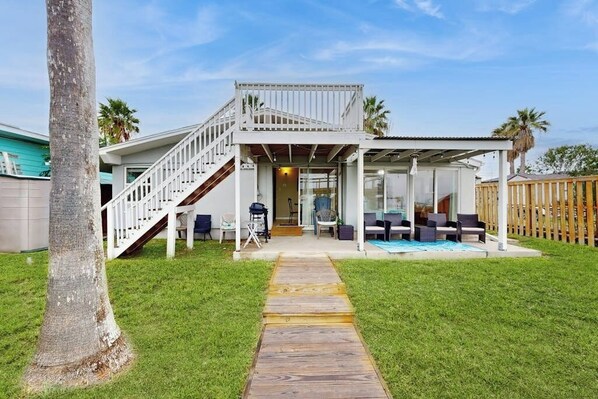 A two-story house with a covered patio, a staircase, and a pool area. - The Seahorse Cottage (Corpus Christi)