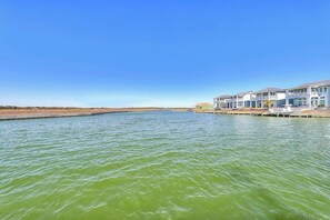 A waterfront property with multiple buildings, a clear sky, and calm water. - Waterfront Villa on St Charles Bay (Rockport)