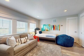 A bedroom with a bed, a sofa, a bean bag, and a large abstract painting on the wall. - Waterfront Villa on St Charles Bay (Rockport)