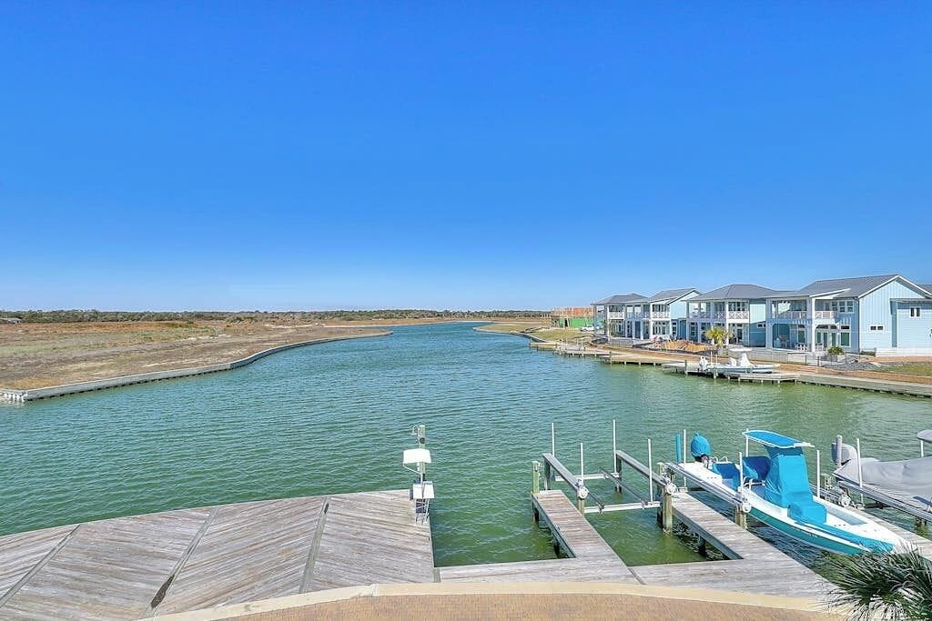 A waterfront property with a dock, a boat, and a row of houses.