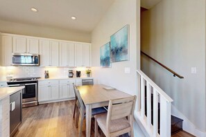 A kitchen with white cabinets, a wooden dining table, and a staircase. - Waterfront Villa on St Charles Bay (Rockport)