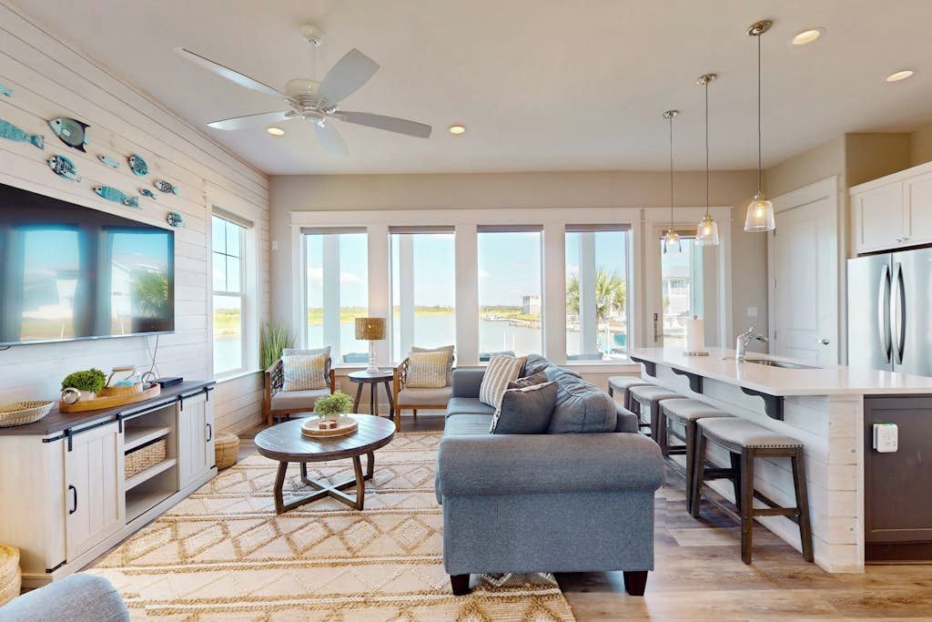 A modern kitchen with a bar area, large windows, and a ceiling fan.