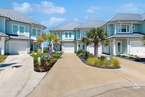 A residential area with multiple houses, a paved driveway, and landscaped gardens with palm trees. - Waterfront Villa on St Charles Bay (Rockport)
