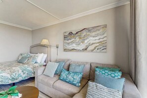 A hotel room with a bed, a sofa, a coffee table, and a painting on the wall. - San Luis Sunshine #631 (Galveston)