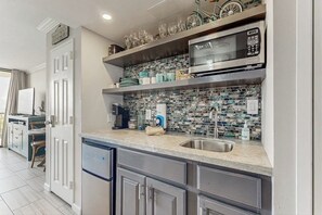 A modern kitchen with a built-in microwave, a sink, and a tiled backsplash. - San Luis Sunshine #631 (Galveston)