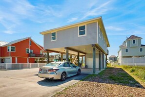 A modern two-story house with a covered garage, a parked car, and a clear sky. - Sandpiper Villa - Beach Views, Pool, Dogs OK (Galveston)