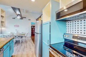 Eine moderne Küche mit Einbauofen, Deckenventilator und Essbereich mit Tisch und Stühlen.