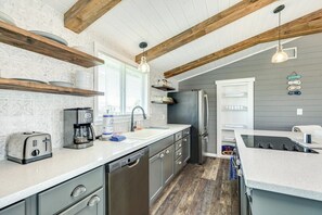 Eine Küche mit Holzbalken, einem Edelstahl-Kühlschrank und einem Geschirrspüler.