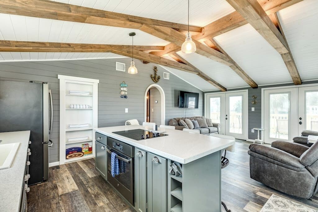 A modern kitchen with a central island, built-in appliances, and a dining area with a sofa.