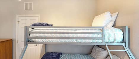 Una cama litera con una cama inferior, una puerta y un pequeño armario de madera.