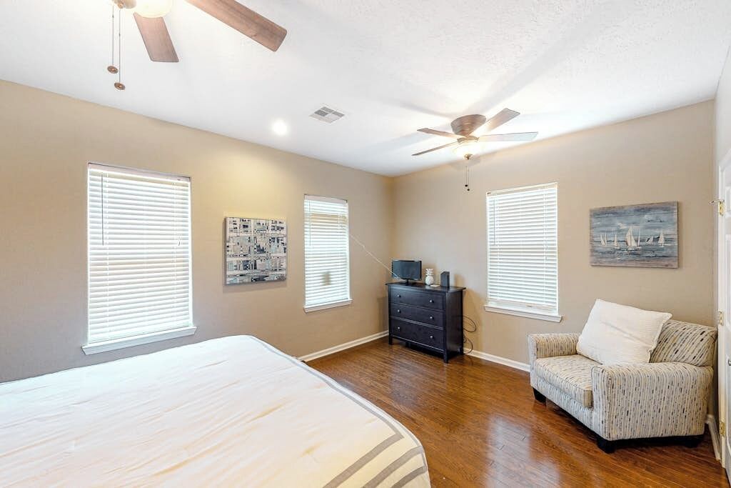 Une chambre à coucher avec un lit, une commode, une chaise et un ventilateur de plafond.