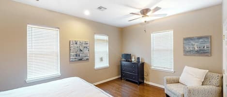 Une chambre à coucher avec un lit, une commode, une chaise et un ventilateur de plafond.