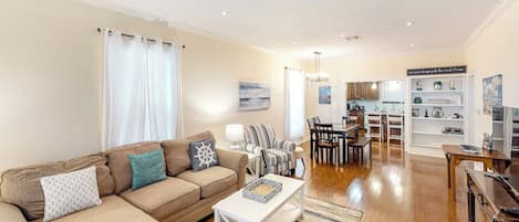 A living room with a sofa, coffee table, and dining area with chairs and a table.