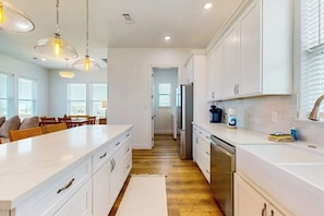 A modern kitchen with white cabinetry, stainless steel appliances, and pendant lighting. - The Green Palm - Bay-View Patio & Shared Pool (Galveston)