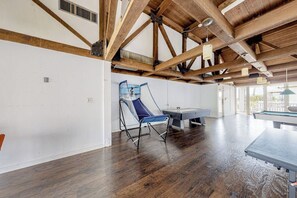 A spacious room with a pool table, a blue folding chair, and a ping pong table. - Gulf Point Condominiums #1314 (South Padre Island)