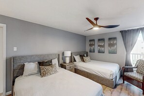 A hotel room with two beds, a ceiling fan, a nightstand with a lamp, and a chair. - Solare Garden Villa 679F (South Padre Island)