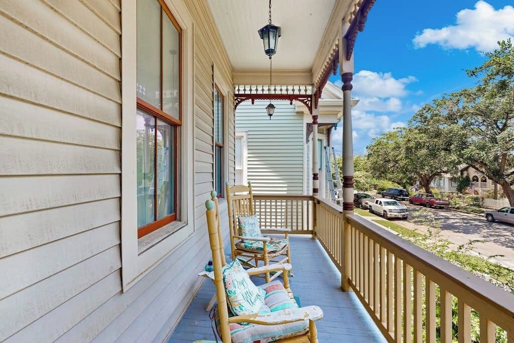 Een veranda met een balustrade, een hanglamp en een rij stoelen.