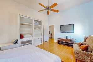 A bedroom with a bed, wardrobe, TV, and seating area. - Under the Avenue - Near the Beach & The Strand (Galveston)
