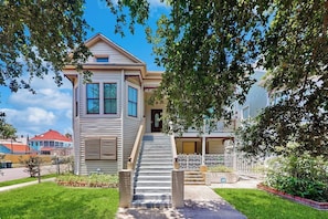 A two-story house with a front porch, a staircase, and a fenced yard. - Under the Avenue - Near the Beach & The Strand (Galveston)