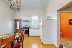 A compact kitchen with white cabinets, a stove, and a refrigerator. - Under the Avenue - Near the Beach & The Strand (Galveston)