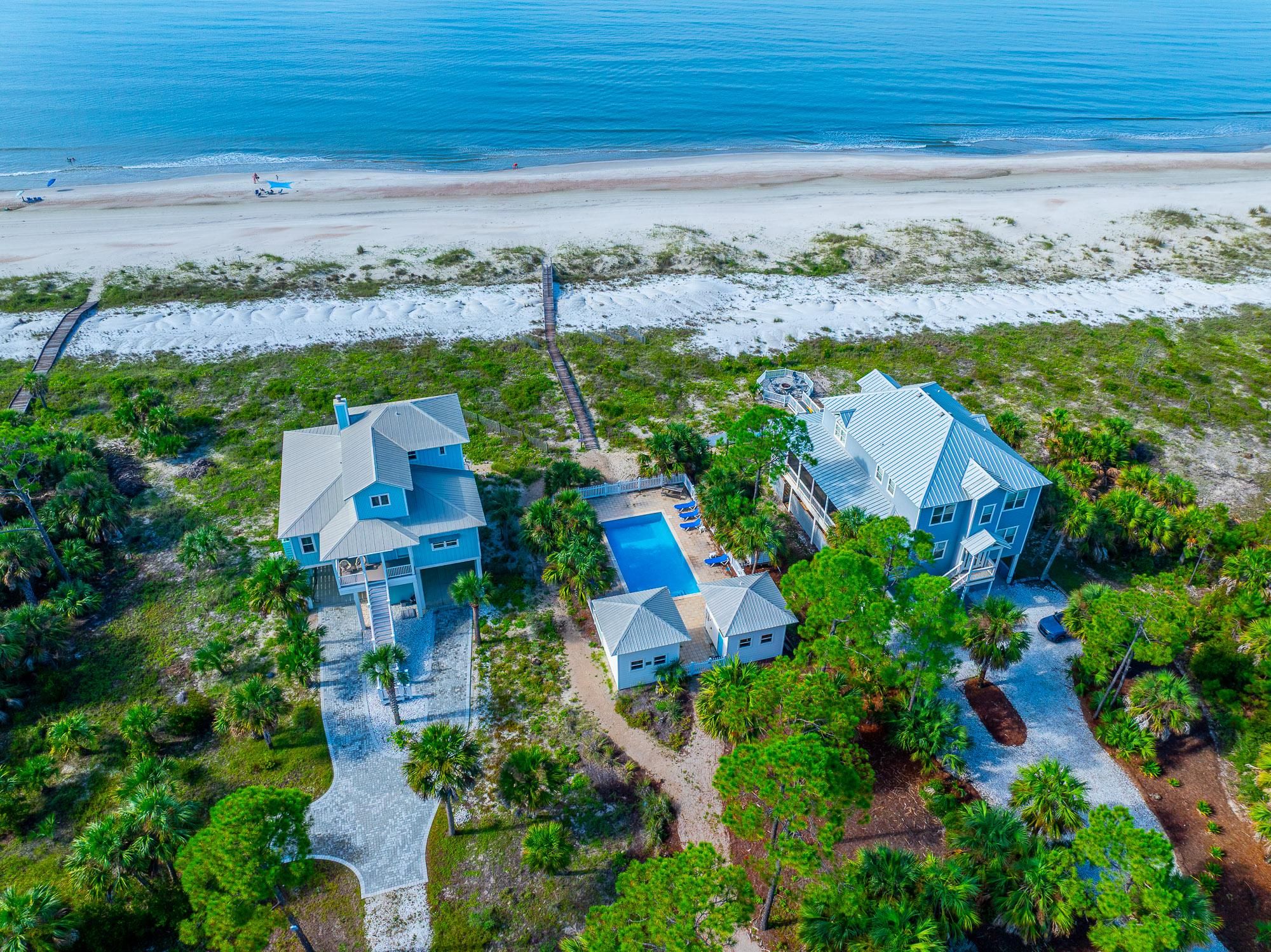 Una propiedad costera con dos edificios principales, piscina y vista a la playa.