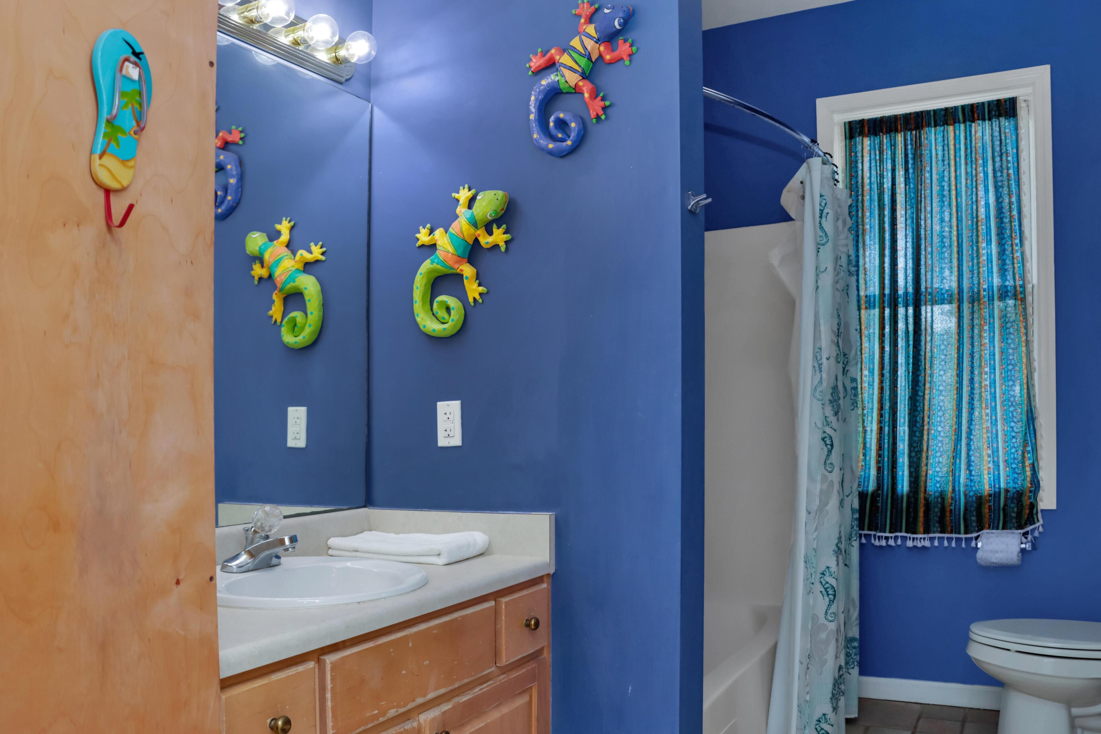 A bathroom with a blue wall, a white sink, a mirror, and a toilet.